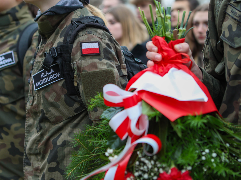 Fotografia przedstawia ucznia szkoły wojskowej trzymającego bukiet kwiatów.