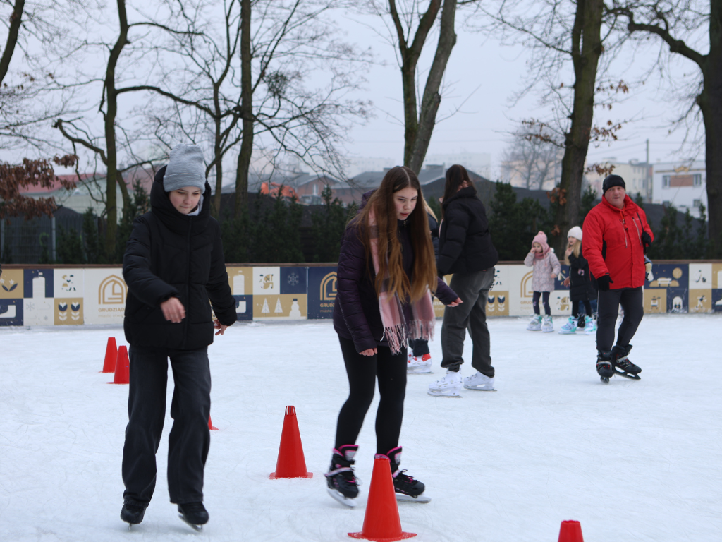 Fotografia przedstawia dzieci jeżdżące na łyżwach. 