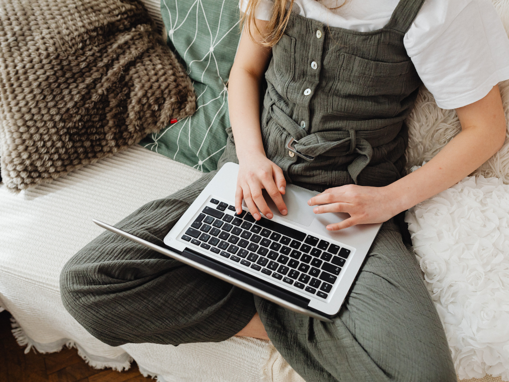 Grafika przedstawia osobę obsługującą laptop. 