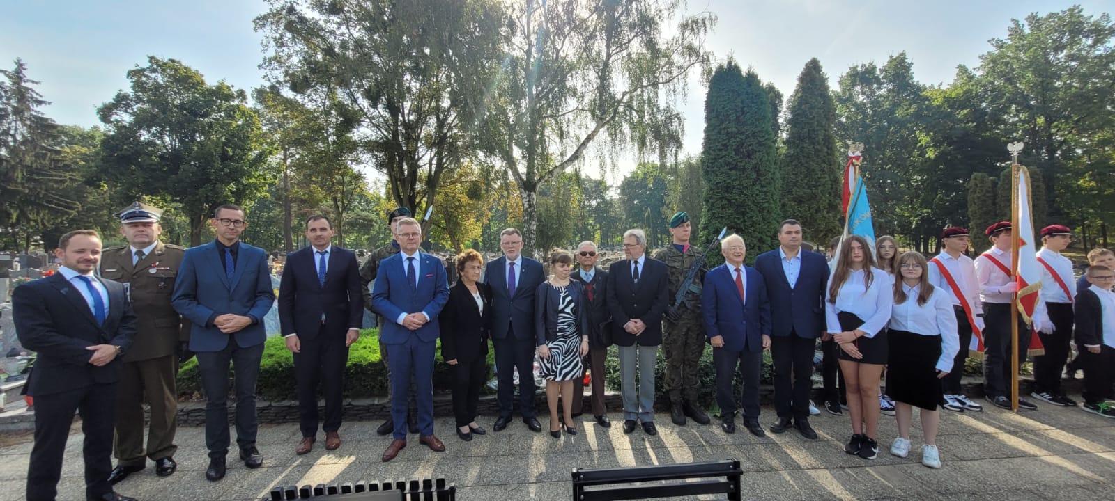 Grafika prezentuje grupowe zdjęcie uczestników obchodów Dnia Sybiraka na cmentarzu przy ul. Cmentarnej w Grudziądzu.